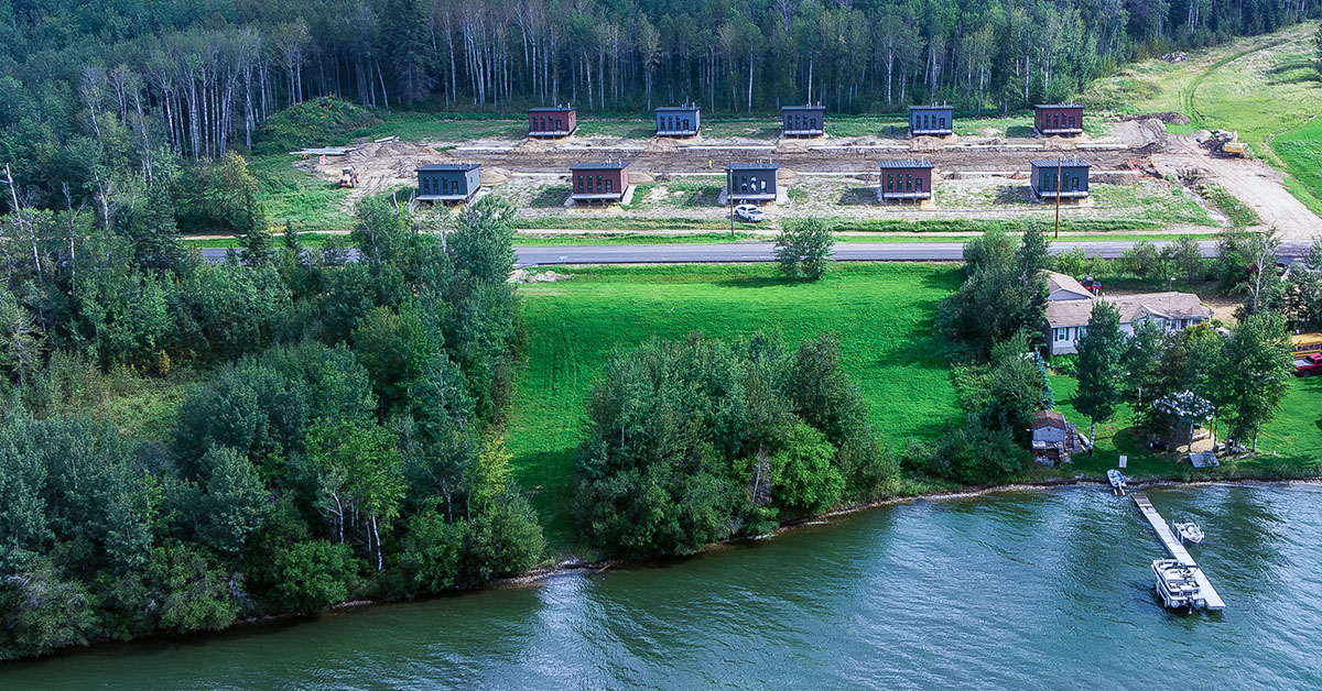 Aerial view of the Calling Lake Elder Suites modular housing development by Pleasant Homes, showcasing the completed site layout along the lakeshore. Project video by Soaring Pig Studios, recipient of an industry award.
